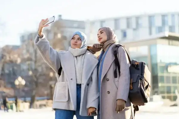two-muslim-female-friends-taking-selfie-while-traveling-city